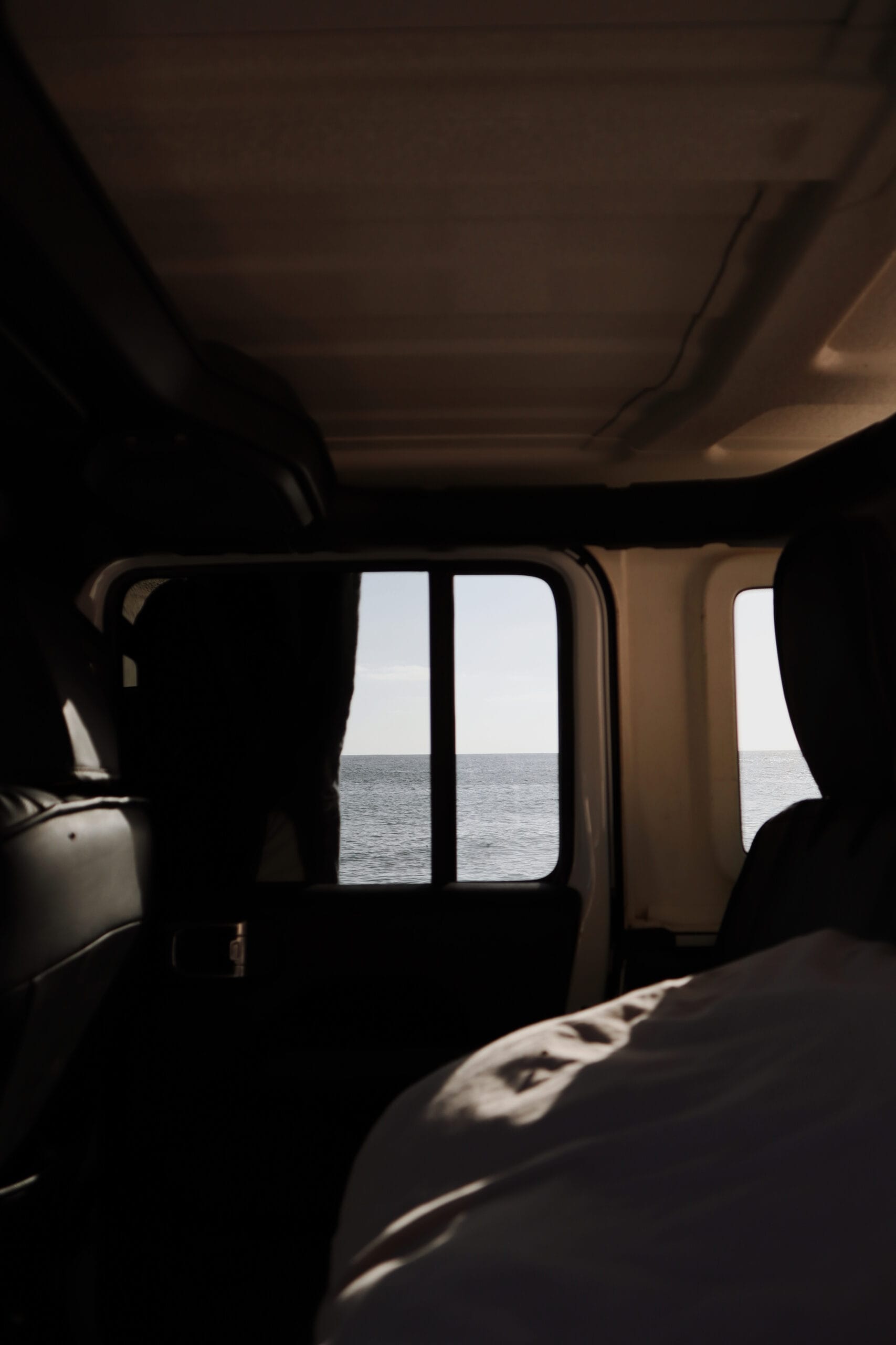 Interior of a 4×4 camper with an ocean view through the window, highlighting comfort and functionality for traveling light in Baja California Sur.