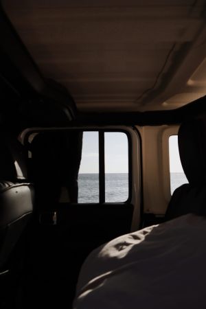 Interior of a 4×4 camper with an ocean view through the window, highlighting comfort and functionality for traveling light in Baja California Sur.